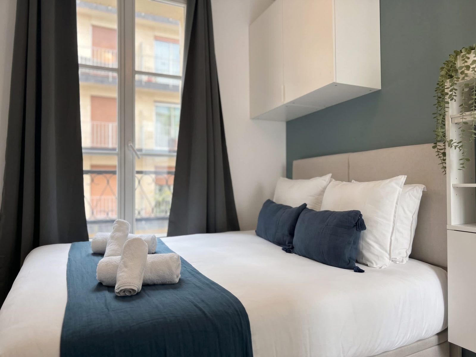 Chambre bleu marine et blanc, rideaux gris et fenêtre sur la rue