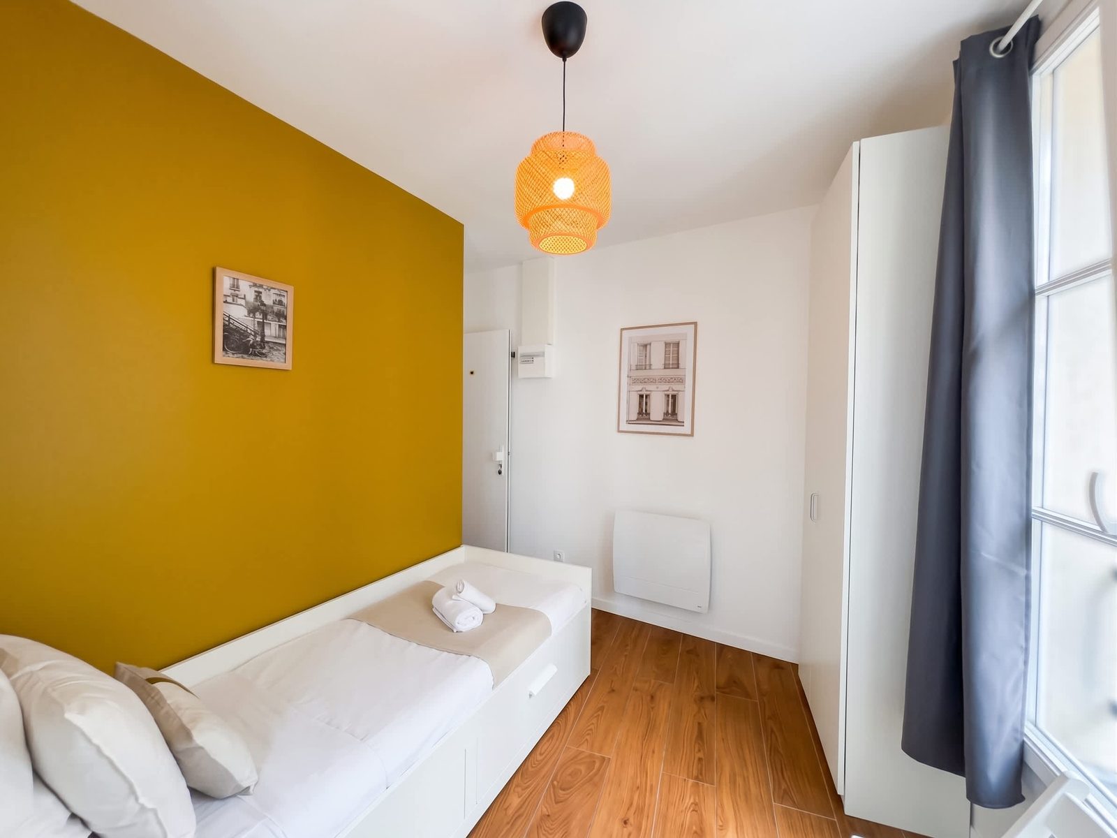 Chambre au mur ocre et suspension en rotin